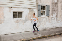 A woman runs in the goodbody goodmommy leggings.